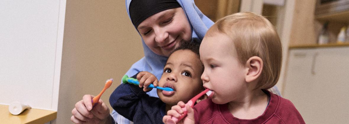Kinderbegeleider met twee kinderen aan het tanden poetsen